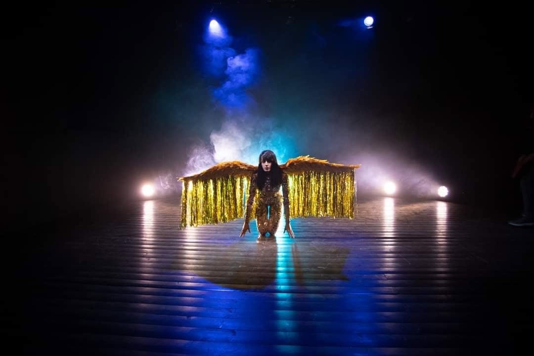 Valentina Black on stage in a gold-winged costume, part of the visual world around "Say You Love the World"